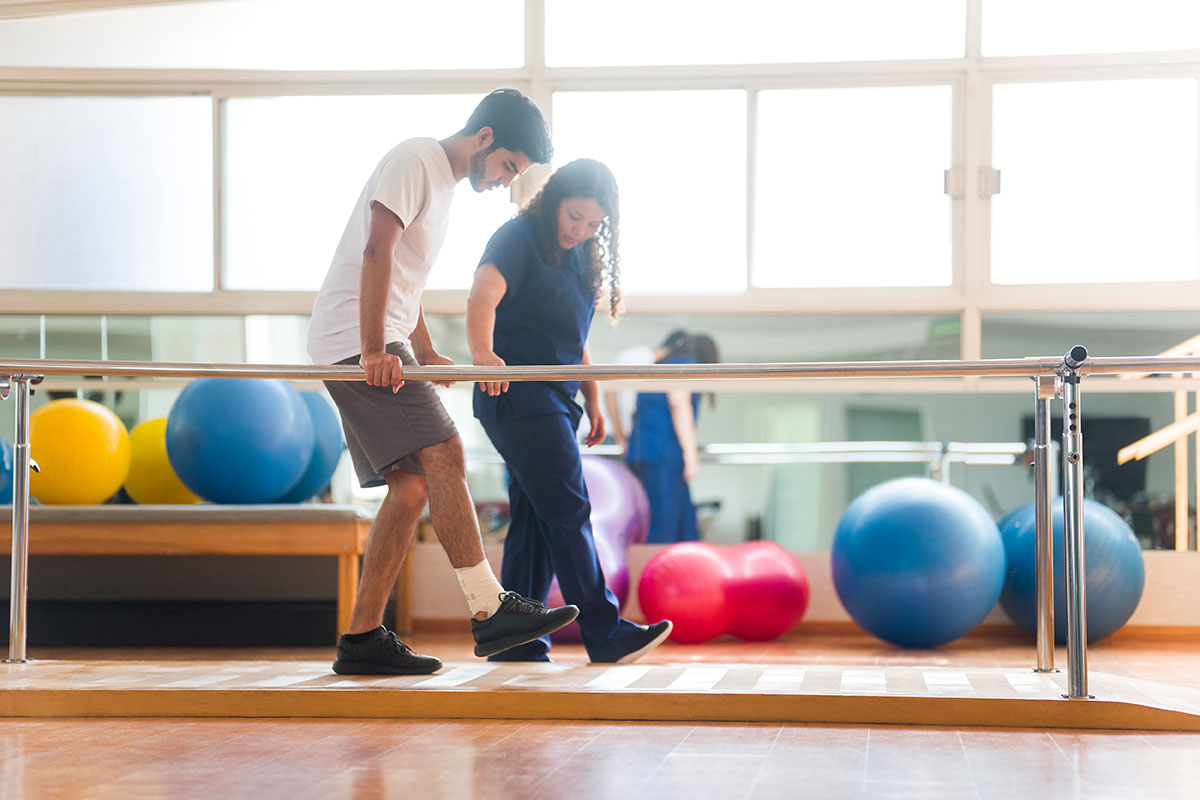 Mann lernt gehen bei Physiotherapie